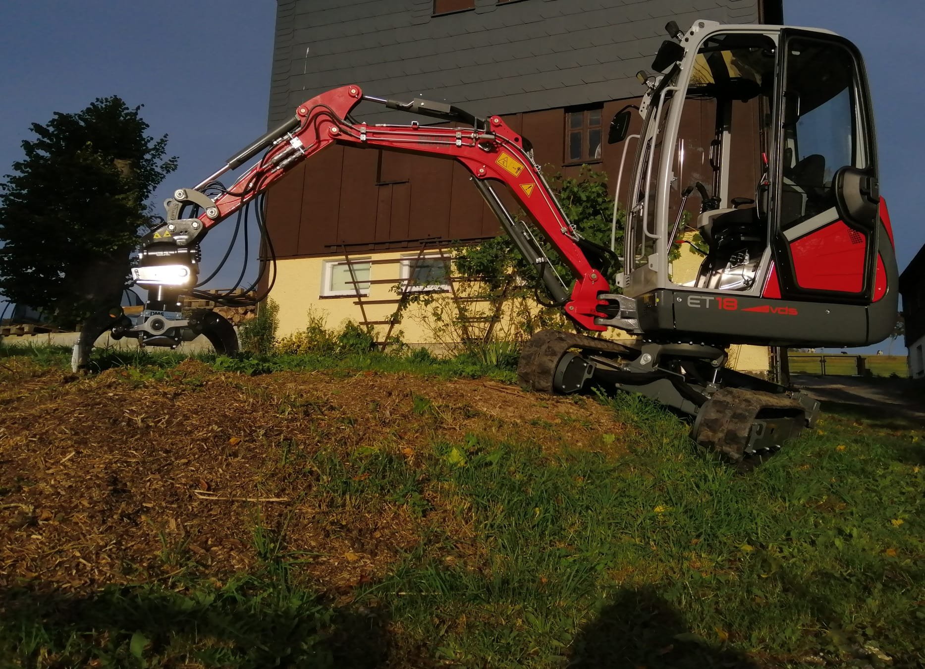 Minibagger bei Erdarbeiten an einer Böschung vor einem Wohnhaus